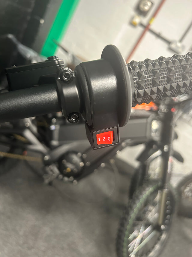 Close-up of a bicycle handlebar with a throttle control switch.