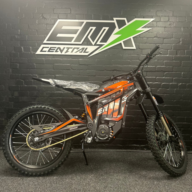 Motorcycle with orange and black design against a black wall with 'EMX Central' logo.