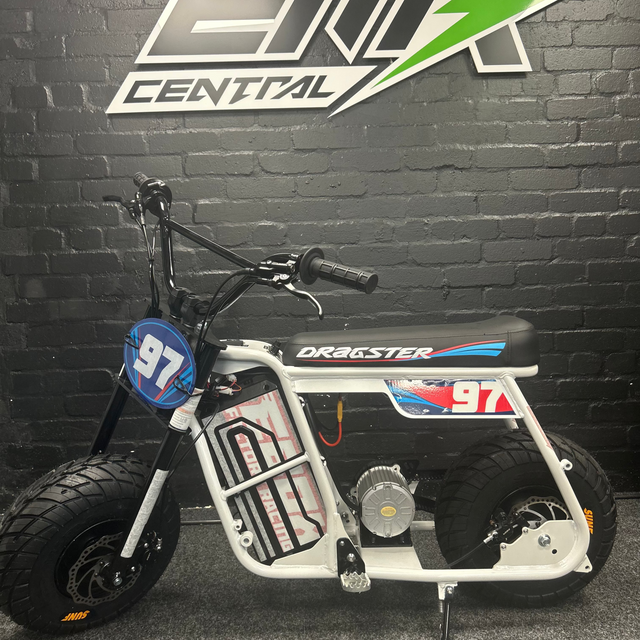 Small motorcycle with 'Dragster' branding on a dark brick wall background