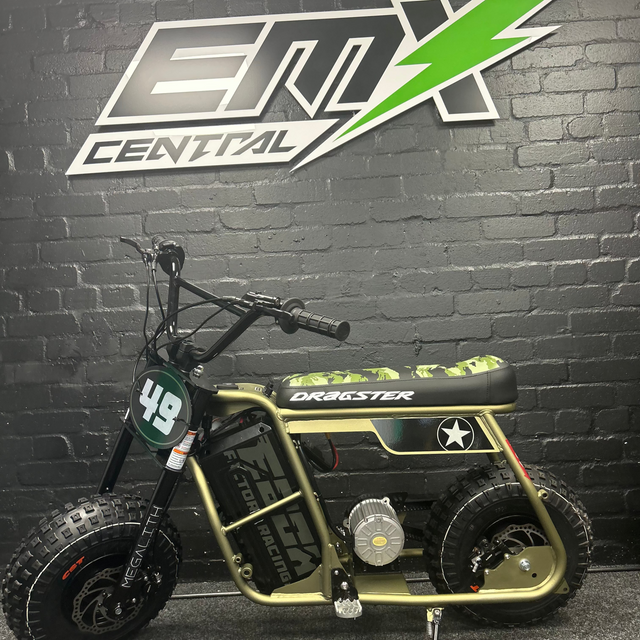 Small off-road vehicle with 'Orbester' branding against a brick wall with 'EMX Central' logo.
