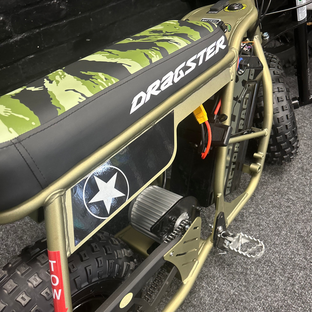 Close-up of a green and black vehicle with 'Dragster' branding on a textured surface.
