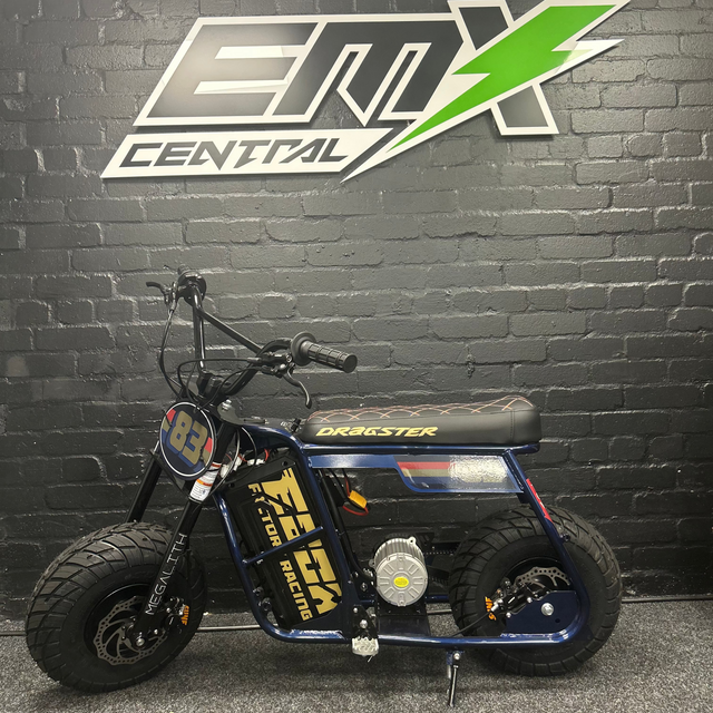 Small electric bike in front of a black brick wall with a logo for EMX Central.