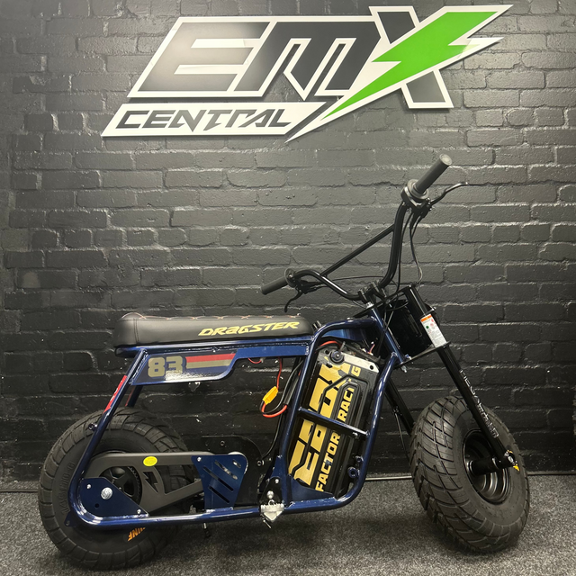 Small electric bike in front of a black brick wall with 'EMX Central' logo.