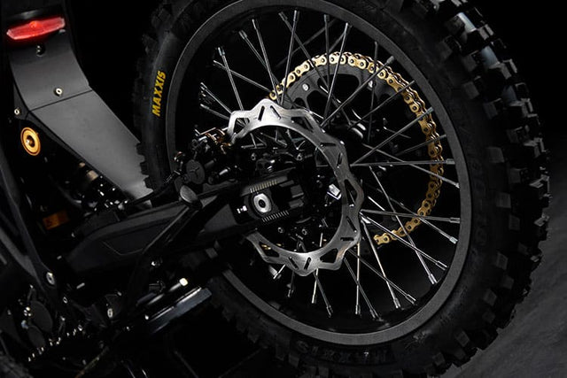 Close-up of a motorcycle wheel with a gold chain on a dark background