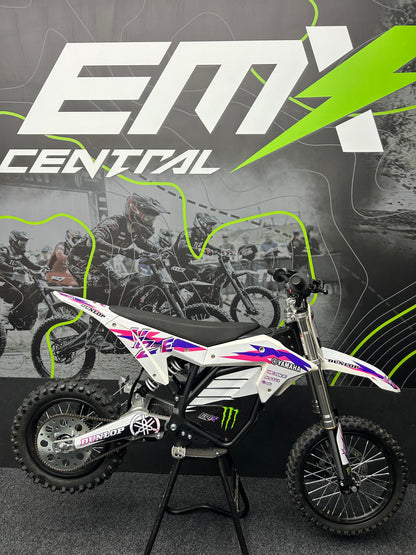 Small dirt bike on a stand with 'EMX Central' branding in the background