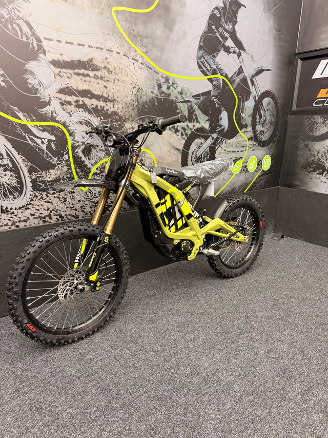 Yellow dirt bike on display with a graphic of a rider in the background