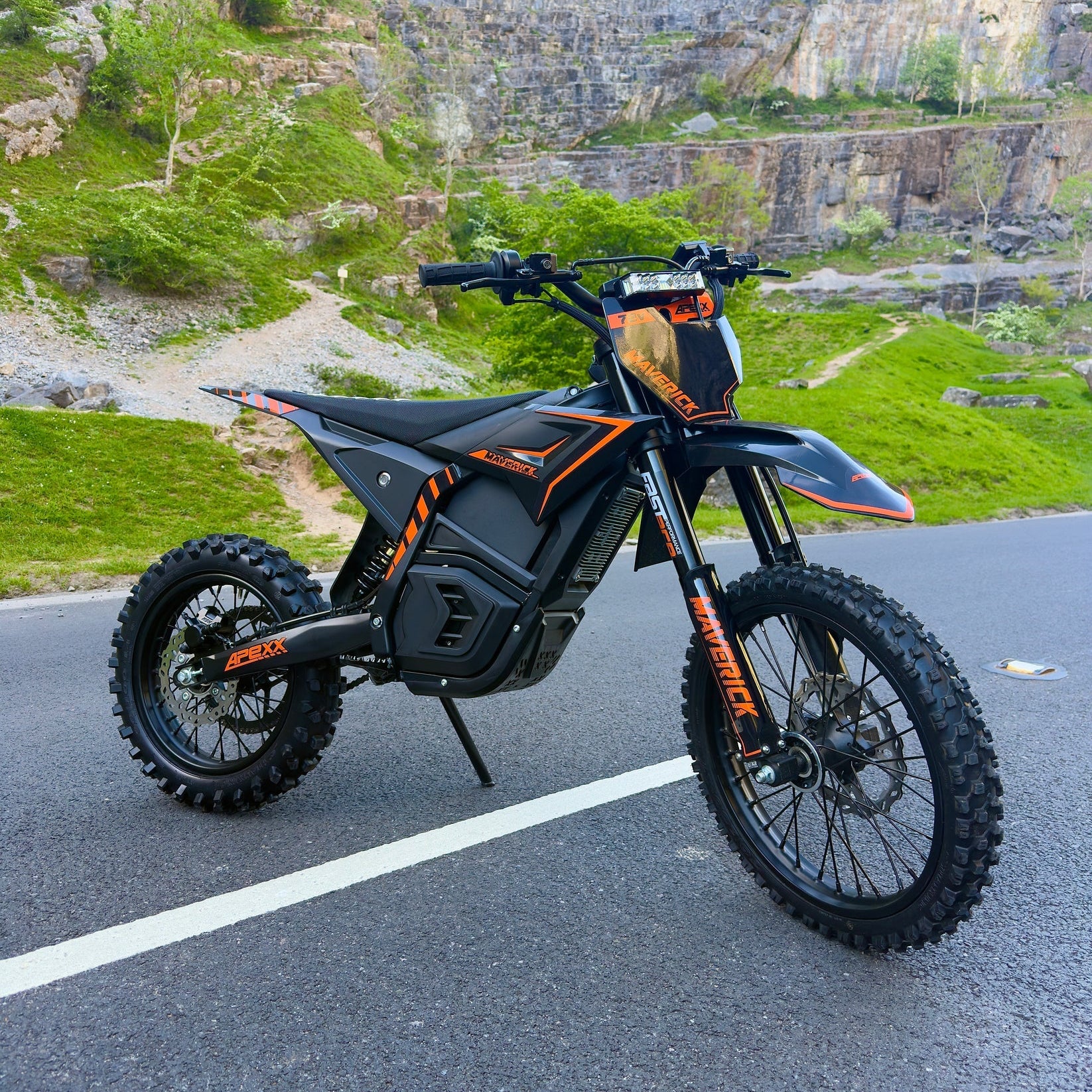 Black and orange electric bike on a road with a rocky landscape in the background