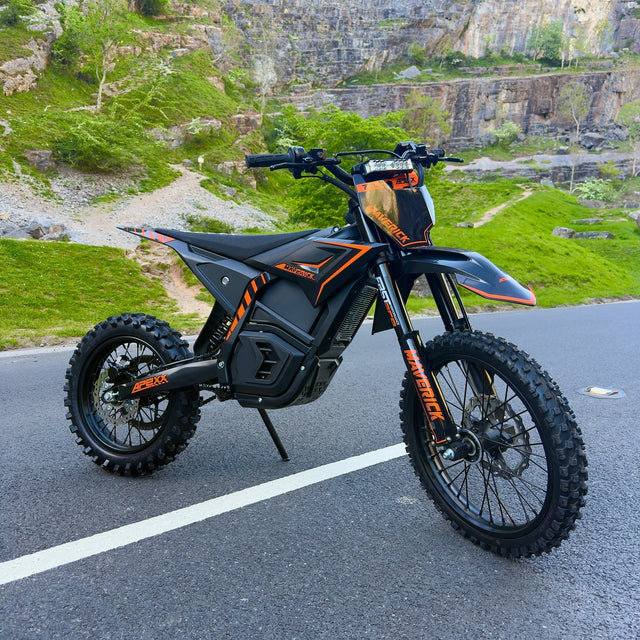 Black and orange electric bike on a road with a rocky landscape in the background