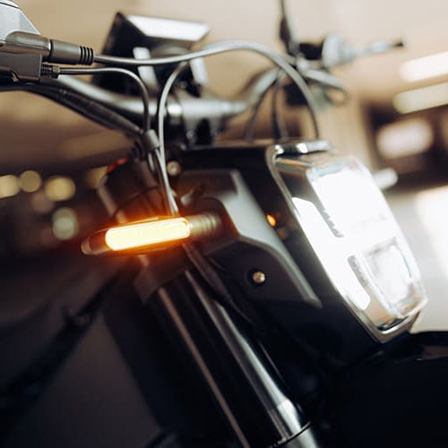 Close-up of a motorcycle's headlight and handlebar with a blurred background