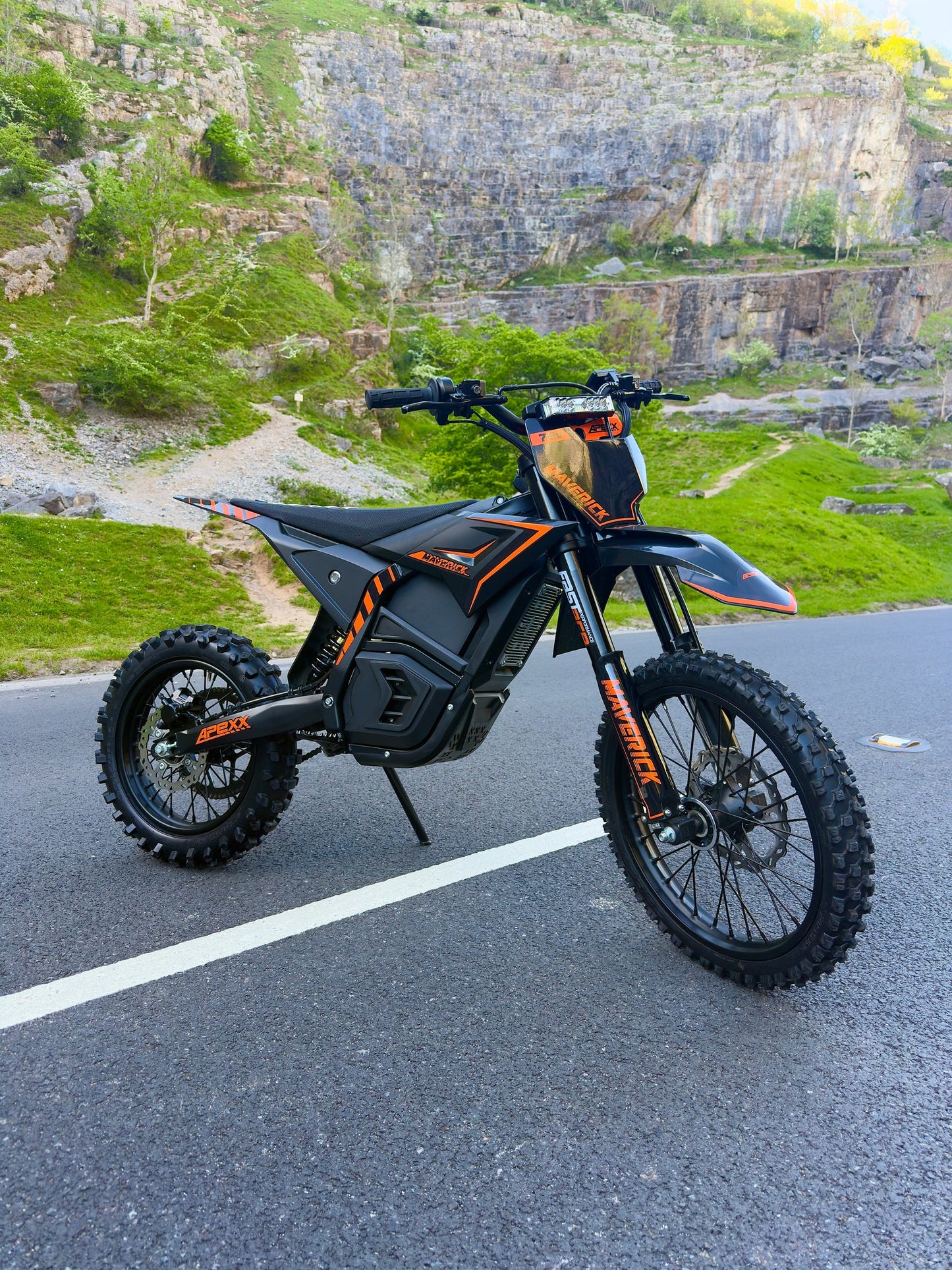 Black and orange electric bike on a road with a rocky landscape in the background
