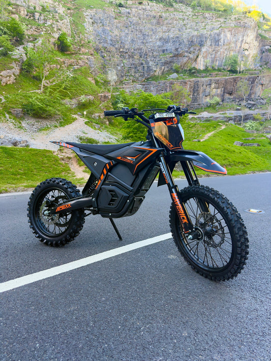 Black and orange electric bike on a road with a rocky landscape in the background