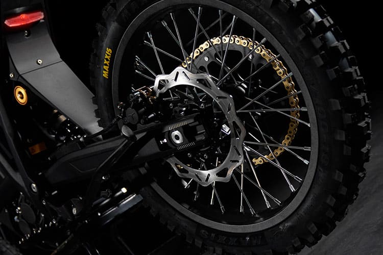 Close-up of a motorcycle wheel with a gold chain on a dark background