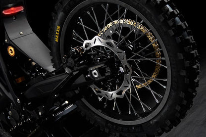 Close-up of a motorcycle wheel with a gold chain on a dark background